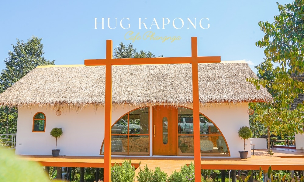 วิวภายนอกของ "hug kapong cafe & nursery" ที่สว่างสดใสในพังงา หลังคามุงจาก และโครงสร้างโครงสีส้ม