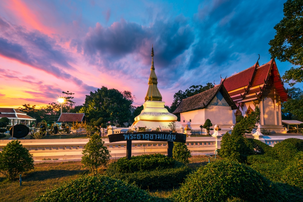 กลุ่มวัดไทยที่มีเจดีย์สีทองและอาคารแบบดั้งเดิม ซึ่งถูกแสงอาทิตย์ยามเย็นส่องสว่าง ท่ามกลางเมฆบนท้องฟ้าที่ดูน่าทึ่ง—สร้างบรรยากาศที่สงบเงียบ ซึ่งทำให้นึกถึงสภาพแวดล้อมที่สงบสุขที่คุณอาจพบได้ที่รีสอร์ทขอนแก่น หรือที่พักขอนแก่นชั้นนำ.