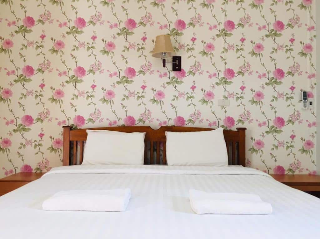 เตียงในห้องที่มีวอลเปเปอร์ลายดอกไม้ รีสอร์ทน่าน