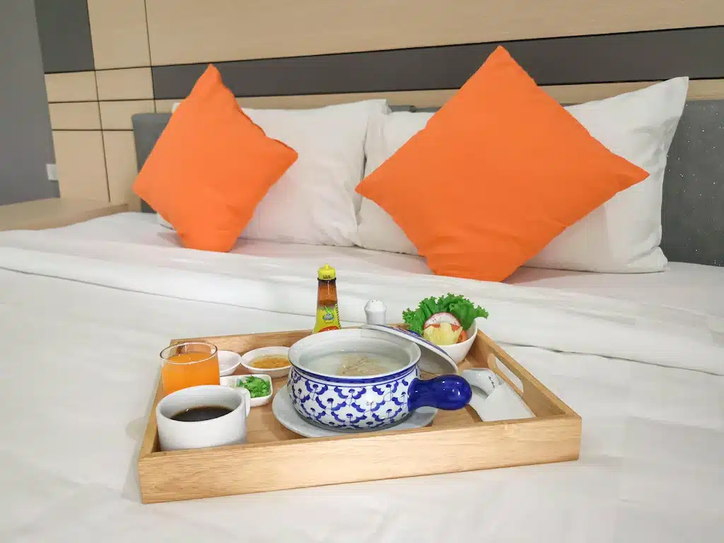 เตียงพร้อมหมอนสีส้มและถาดวางอาหาร เหมาะสำหรับการพักผ่อนอย่างผ่อนคลาย  สถานที่ท่องเที่ยวหาดใหญ่