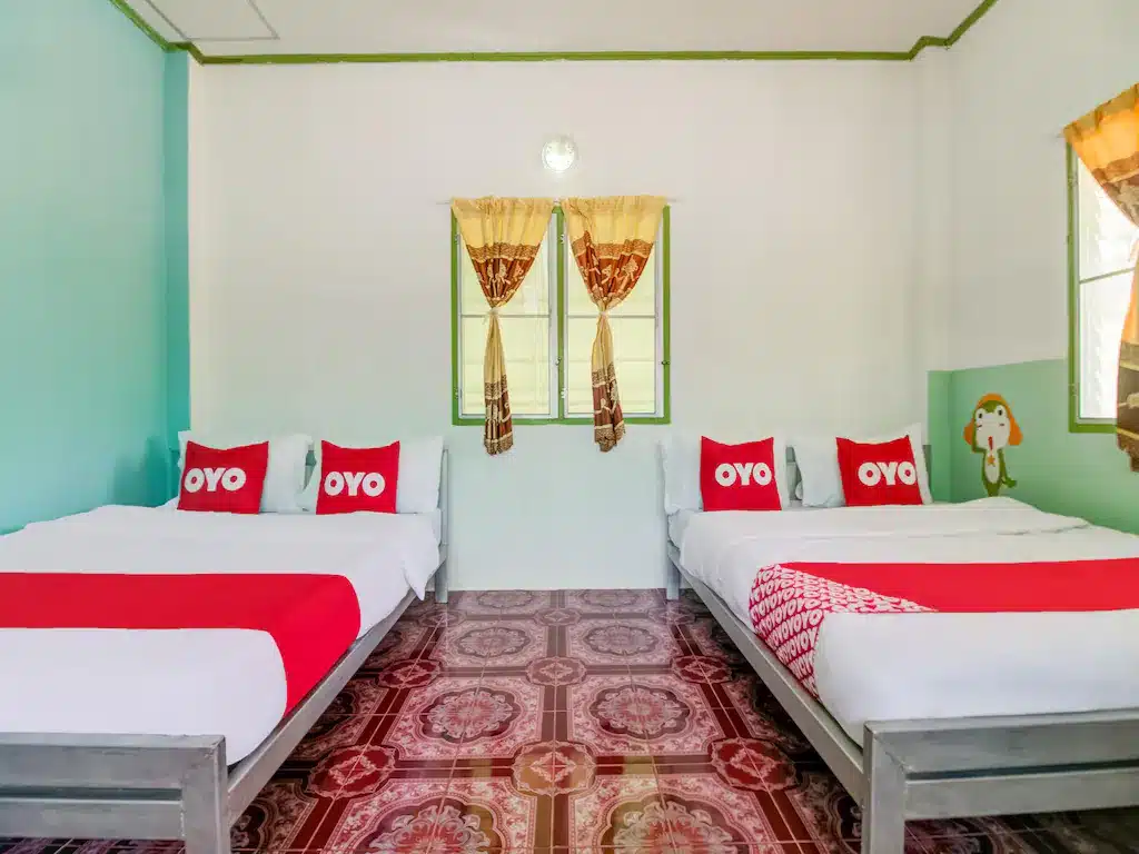 เตียงสองเตียงในห้องที่มีผนังสีแดงและสีเขียวใกล้ชายหาดในจังหวัดชุมพร รีสอร์ทแก่งกระจาน