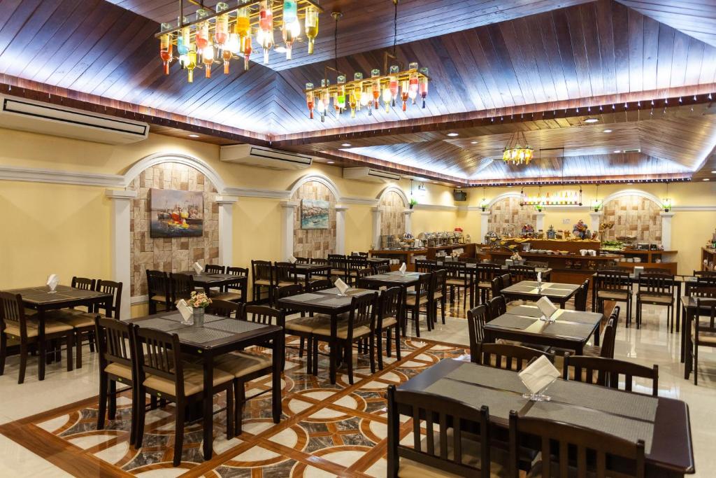 ห้องอาหารกว้างขวางในโรงแรมเชียงใหม่ โดดเด่นด้วยโต๊ะและเก้าอี้ไม้สีเข้ม แสงไฟตกแต่ง กำแพงประดับด้วยงานศิลปะ บาร์ที่ตั้งอยู่ด้านหลัง และเพดานไม้ที่หรูหรา.