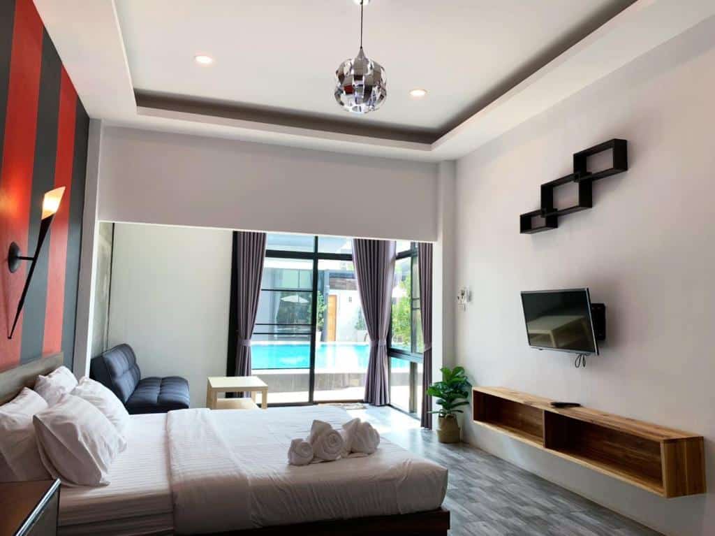 ห้องพักโรงแรมสมัยใหม่ที่ โรงแรมน่าน พร้อมเตียง โซฟา ทีวีติดผนัง ชั้นวางของ และหน้าต่างบานใหญ่ที่มองเห็นสระว่ายน้ำ ผ้าเช็ดตัวจัดวางอย่างเรียบร้อยบนเตียง—เหมาะอย่างยิ่งสำหรับประสบการณ์การพักผ่อนของคุณใน น่าน.