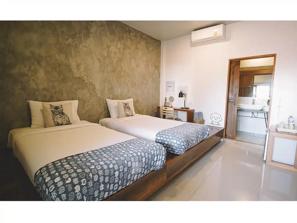 ห้องพักโรงแรมสมัยใหม่ที่ โรงแรมเชียงราย พร้อมเตียงเดี่ยวสองเตียง โต๊ะทำงานไม้ เครื่องปรับอากาศ และวิวห้องน้ำในตัว—เหมาะสำหรับการเข้าพักของคุณในเชียงราย.