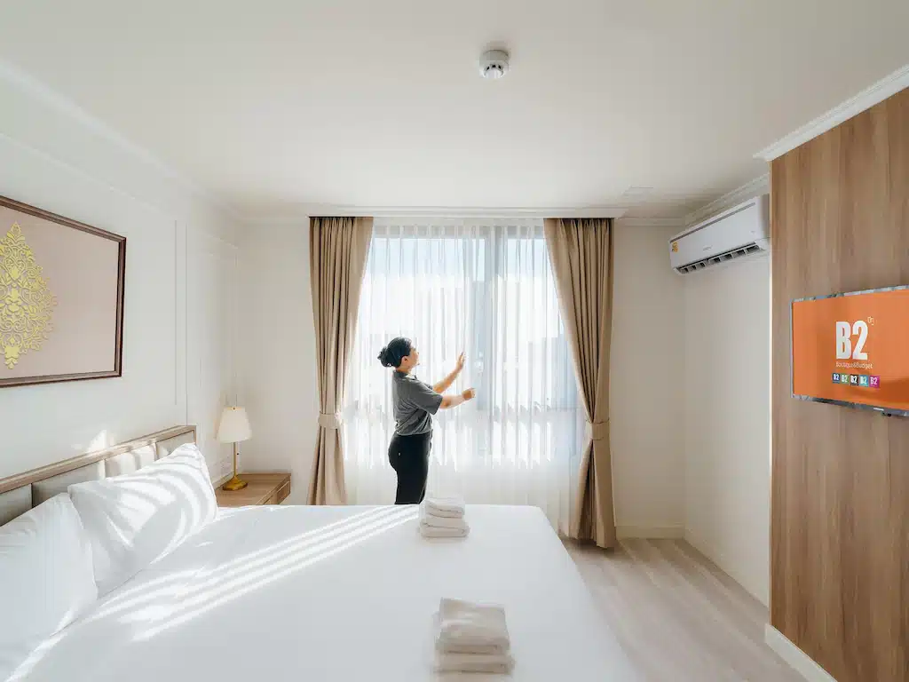 ผู้หญิงคนหนึ่งยืนอยู่ในห้องพักที่อบอุ่นในโรงแรมเชียงใหม่ กำลังเพลิดเพลินกับบรรยากาศที่สบาย.