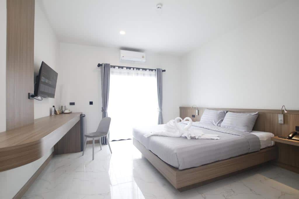 ห้องพักโรงแรมสมัยใหม่ในเชียงราย พร้อมเตียงคู่ โทรทัศน์ติดผนัง โต๊ะทำงาน เก้าอี้ และหน้าต่างบานใหญ่พร้อมผ้าม่าน ผ้าเช็ดตัวบนเตียงพับเป็นรูปหงส์อย่างสวยงาม.