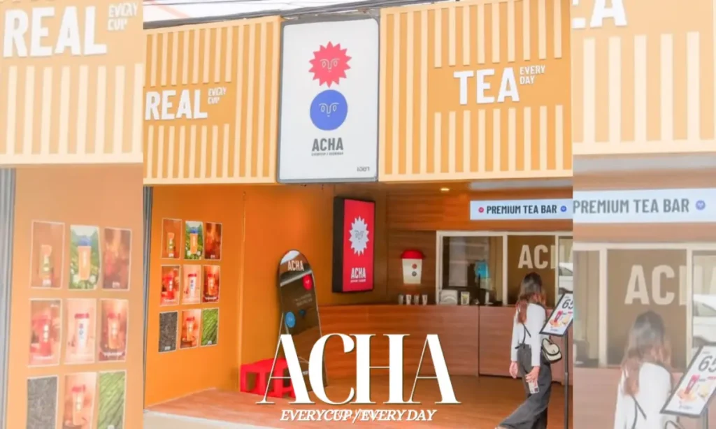 ผู้หญิงคนหนึ่งเดินเข้าไปในร้านชาที่สว่างไสวชื่อว่า ACHA ซึ่งมีผนังสีส้มและป้ายที่เขียนว่า "ชาแท้ทุกวัน" และ "บาร์ชาพรีเมียม" ซึ่งชวนให้นึกถึงร้านอาหารที่มีชีวิตชีวาซึ่งเสิร์ฟ ข้าวมันไก่สิงคโปร์ ภูเก็ต ที่อยู่ใกล้เคียง.