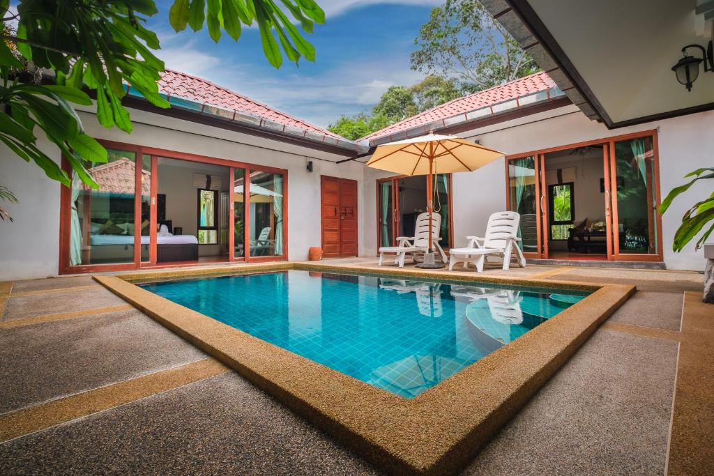 สระว่ายน้ำกลางแจ้งขนาดเล็ก ล้อมรอบด้วยลานหินอ่อน เก้าอี้อาบแดดสองตัว และร่ม ตั้งอยู่ในลานกลางของวิลล่าสมัยใหม่ที่มีประตูบานเลื่อนกระจก—เหมาะสำหรับการผ่อนคลายที่ที่พักขนอมในระหว่างการเข้าพักของคุณ.