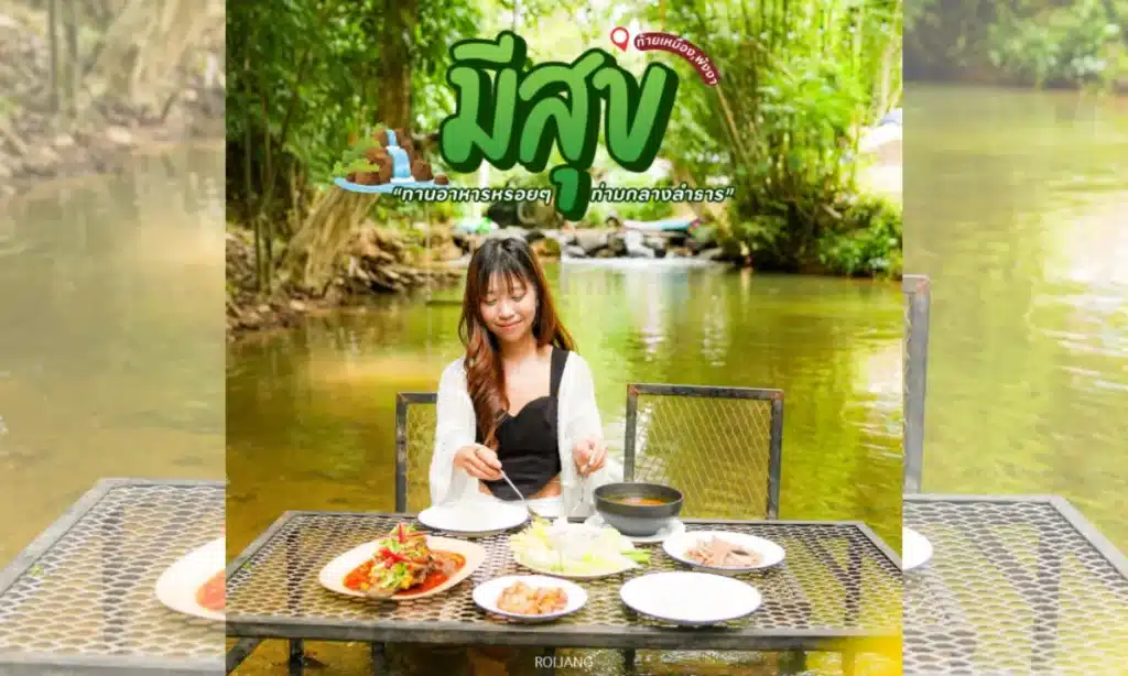 ผู้หญิงคนหนึ่งนั่งอยู่คนเดียวที่โต๊ะซึ่งจัดเตรียมอาหารหลากหลายไว้รอบตัว นั่งรับประทานอาหารกลางแจ้งริมลำธารที่รายล้อมไปด้วยต้นไม้เขียวชอุ่ม เพลิดเพลินกับช่วงเวลาแห่งความสุขท่ามกลางความสงบของธรรมชาติ.