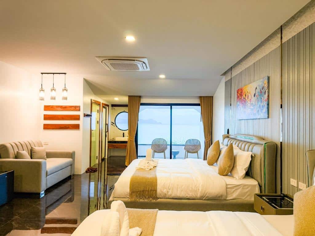 ห้องพักโรงแรมสมัยใหม่ที่ โรงแรมขนอม พร้อมเตียงคู่สองเตียง, โซฟา, ศิลปะติดผนัง, และประตูบานเลื่อนกระจกที่นำไปสู่ระเบียงพร้อมวิวทะเลที่สวยงาม.