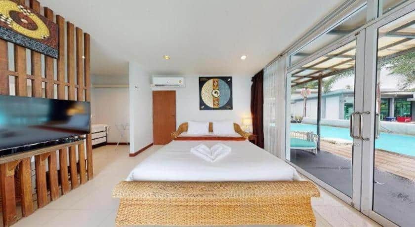 ห้องพักโรงแรม ขนอม ที่ทันสมัยพร้อมเตียงคู่ ทีวี และประตูกระจกบานเลื่อนเปิดออกสู่ระเบียงริมสระว่ายน้ำ ผ้าขนหนูสะอาดพับเรียบร้อยบนเตียง และงานศิลปะท้องถิ่นประดับผนังเพื่อความผ่อนคลายตลอดการเข้าพัก.