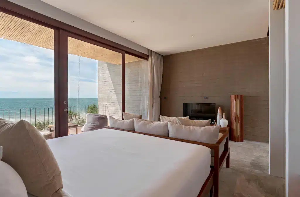 ห้องนอนริมทะเลสไตล์โมเดิร์นที่รีสอร์ทขนอม พร้อมเตียงขนาดใหญ่ ตกแต่งโทนสีเรียบง่าย หน้าต่างกระจกบานใหญ่จากพื้นจรดเพดาน และวิวทะเลที่สวยงามตระการตา.
