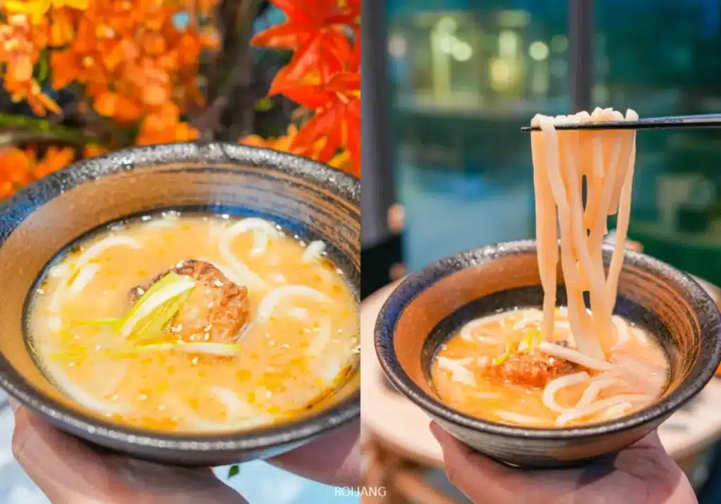 ชามบะหมี่อุด้งน้ำซุปพร้อมเนื้อและผักถูกแสดงที่ร้านบูนต้า กริลล์; ในภาพที่สอง ไม้ตะเกียบกำลังยกเส้นอุด้งขึ้นจากชาม.