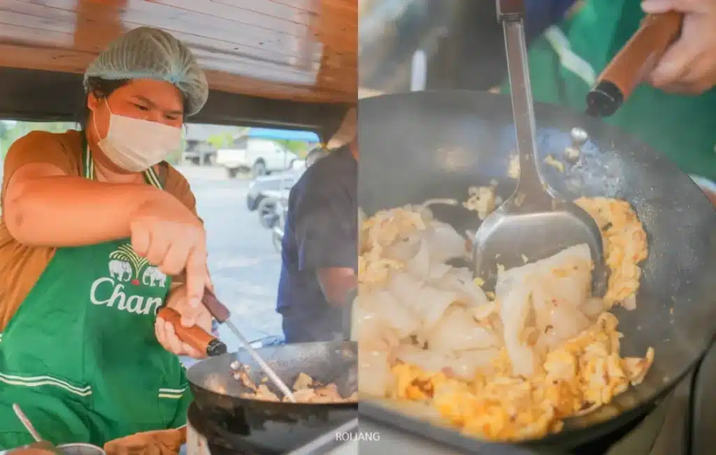 บุคคลที่สวมหน้ากากและหมวกคลุมผมกำลังทำอาหารด้วยหม้อในเตาพร้อมด้วย มีสุข ภาพระยะใกล้แสดงให้เห็นเส้นก๋วยเตี๋ยวและไข่คนกำลังถูกคนด้วยตะหลิวโลหะ สร้างมื้ออาหารที่อร่อยและทำให้รู้สึกดีขึ้น.