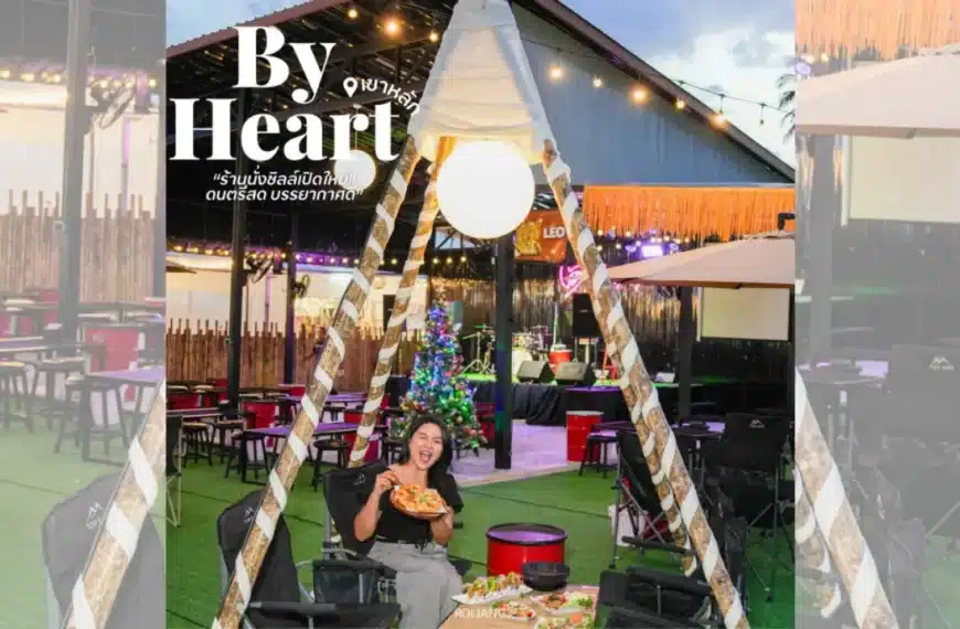 ผู้หญิงคนหนึ่งนั่งอยู่ภายในเต็นท์ที่ตั้งอยู่ในร้านอาหารกลางแจ้ง ถือพิซซ่าไว้ในมือ บริเวณนั้นประดับด้วยไฟ โต๊ะ และต้นคริสต์มาส—ถ่ายทอดบรรยากาศอบอุ่นของเทศกาลวันหยุดได้อย่างเต็มเปี่ยม.