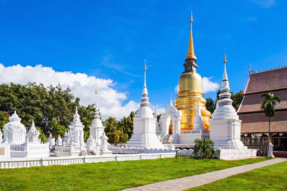 เจดีย์สีขาวและเจดีย์ทองคำตั้งตระหง่านท่ามกลางท้องฟ้าสีฟ้าสดใส ณ วัดพุทธอันเงียบสงบแห่งนี้ ล้อมรอบด้วยพืชพรรณเขียวชอุ่ม—สถานที่ท่อง เที่ยวเชียงใหม่ ที่ไม่ควรพลาดสำหรับผู้ที่ต้องการสำรวจมรดกทางวัฒนธรรมอันรุ่มรวยของภูมิภาค.