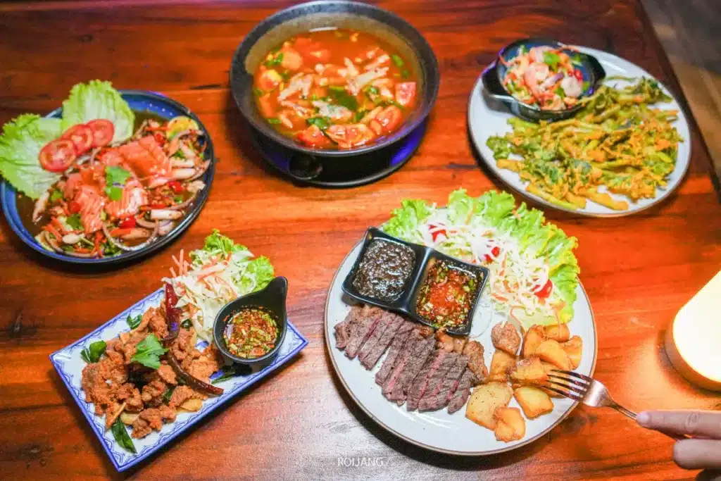 โต๊ะที่ The Rooftop มีอาหารหลากหลายให้เลือก เช่น สเต็กเนื้อสไลซ์พร้อมมันฝรั่งและน้ำจิ้ม ผักทอด ซุป จานเนื้อทอด สลัด และอาหารทะเล.