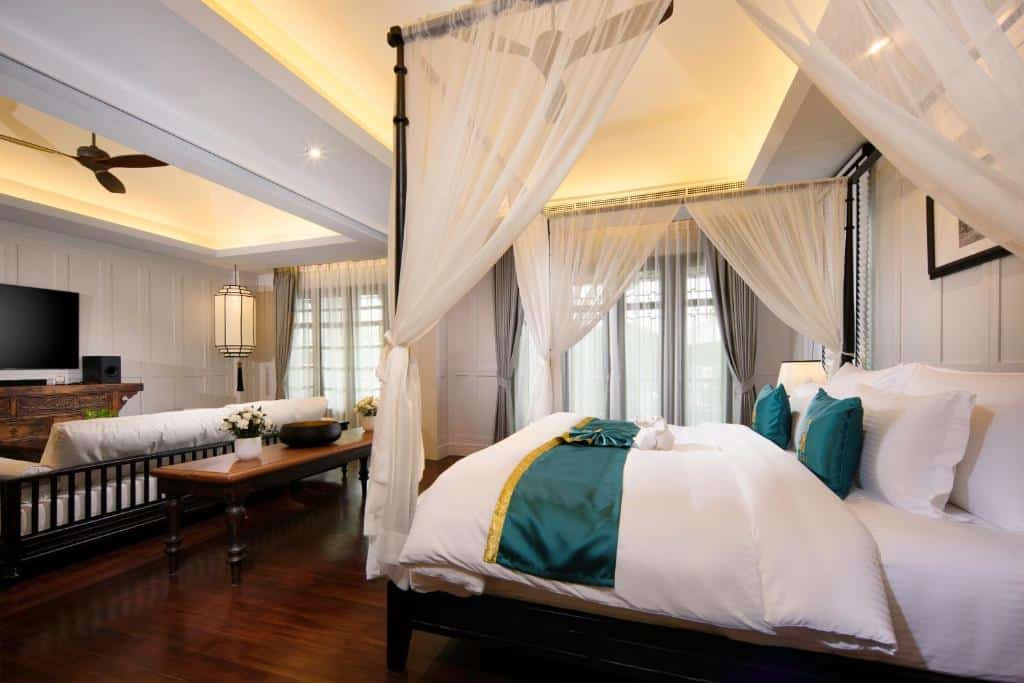 ห้องนอนกว้างขวางพร้อมเตียงทรงหลังคาโปร่งสีเขียวอมฟ้าและขาว มีพื้นที่นั่งเล่น พื้นไม้ และหน้าต่างบานใหญ่พร้อมผ้าม่านบาง เหมาะสำหรับผู้ที่มองหาที่พักเชียงใหม่ท่ามกลางธรรมชาติในบรรยากาศเงียบสงบ.