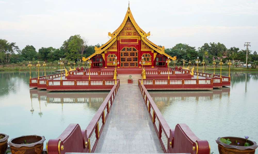 วัดแบบดั้งเดิมสีแดงและทองตั้งอยู่บนเกาะในทะเลสาบ สามารถเข้าถึงได้ผ่านสะพานกลาง และล้อมรอบไปด้วยต้นไม้สีเขียว—สถานที่เงียบสงบเหมาะสำหรับผู้ที่กำลังมองหาสถานที่ท่องเที่ยวในบุรีรัมย์เพื่อสำรวจธรรมชาติและวัฒนธรรม.