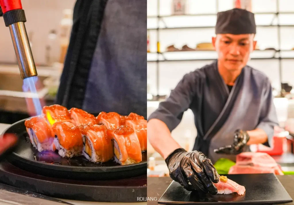 เชฟในชุดเครื่องแบบกำลังเตรียมซูชิ; ทางด้านซ้าย ซูชิโรลที่ได้แรงบันดาลใจจากหุบเขาหมอกกำลังถูกเผาด้วยไฟจากเครื่องเป่าไฟ.