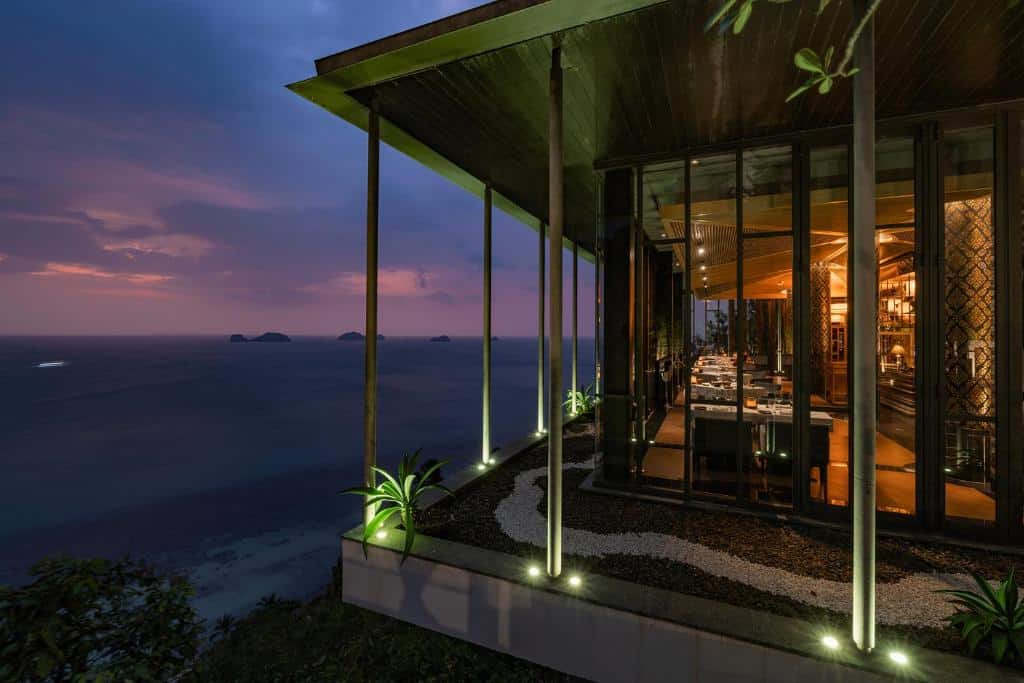 ร้านอาหารสมัยใหม่ที่มีผนังกระจกตั้งอยู่บนหน้าผา มองเห็นทะเลยามพระอาทิตย์ตกดิน พร้อมด้วยแสงไฟภายในที่อบอุ่นและพืชพรรณขนาดเล็กในบริเวณกลางแจ้ง มอบประสบการณ์การรับประทานอาหารที่ลืมไม่ลงให้กับแขกของโรงแรมเกาะสมุย ท่ามกลางวิวทิวทัศน์ที่งดงามจนแทบนึกไม่ถึง.