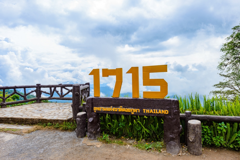 ตัวเลขสีเหลืองขนาดใหญ่ "1715" และป้ายที่เขียนว่า "Thailand" เป็นจุดสังเกตการณ์บนที่สูง โดยมีท้องฟ้าครึ้มและพืชพรรณเขียวชอุ่มเป็นฉากหลัง — ทำให้ที่นี่เป็นหนึ่งในสถานที่ท่องเที่ยวน่านที่ไม่ควรพลาด สำหรับผู้ที่ต้องการสัมผัสความงามตามธรรมชาติของน่านอย่างเต็มที่.