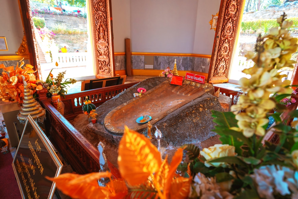 ห้องพระที่ตกแต่งอย่างวิจิตร มีหินโบราณขนาดใหญ่คล้ายรอยเท้าตั้งอยู่ตรงกลาง ล้อมรอบด้วยดอกไม้ ของถวาย และเครื่องประดับทองที่วิจิตรบรรจง — เป็นสถานที่ที่ไม่ควรพลาดสำหรับผู้ที่มาเที่ยวเชียงคาน และใครก็ตามที่ต้องการค้นพบสถานที่ท่องเที่ยวในเชียงคานที่มีเอกลักษณ์และเต็มไปด้วยประวัติศาสตร์.