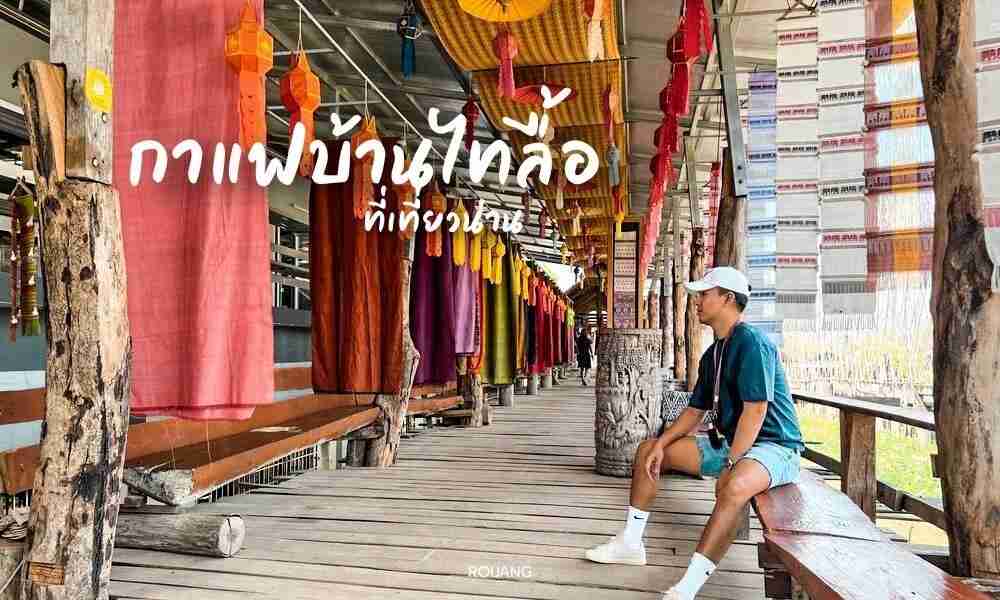 ชายคนหนึ่งสวมชุดลำลองนั่งอยู่บนม้านั่งไม้ในทางเดินที่ตกแต่งอย่างสวยงาม ด้วยผ้าแขวนสีสันสดใสและข้อความภาษาไทยบนภาพ ซึ่งเชิญชวนให้คุณมาค้นพบ เที่ยวน่าน และสำรวจ ที่เที่ยวน่าน ที่ไม่เหมือนใคร.