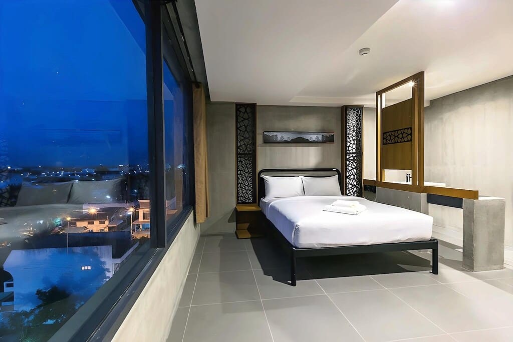 ห้องพักโรงแรมสไตล์โมเดิร์น พร้อมเตียงคู่ที่จัดแต่งอย่างเรียบร้อย หน้าต่างขนาดใหญ่ที่มองเห็นแสงไฟของเมือง พื้นปูกระเบื้อง และการตกแต่งแบบมินิมัล—เหมาะอย่างยิ่งสำหรับแขกที่มองหาที่พักขอนแก่นที่มีสไตล์ หรือประสบการณ์การเข้าพักที่โรงแรมขอนแก่นในใจกลางเมือง.