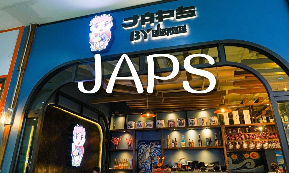 หน้าร้านมีหน้าร้านเป็นสีฟ้าดำ ป้าย JAPS ชวนให้นึกถึง ร้านอาหารตะกั่วป่า มีโลโก้พร้อมตัวการ์ตูนอยู่เหนือทางเข้า เผยให้เห็นชั้นวางและขวดด้านใน