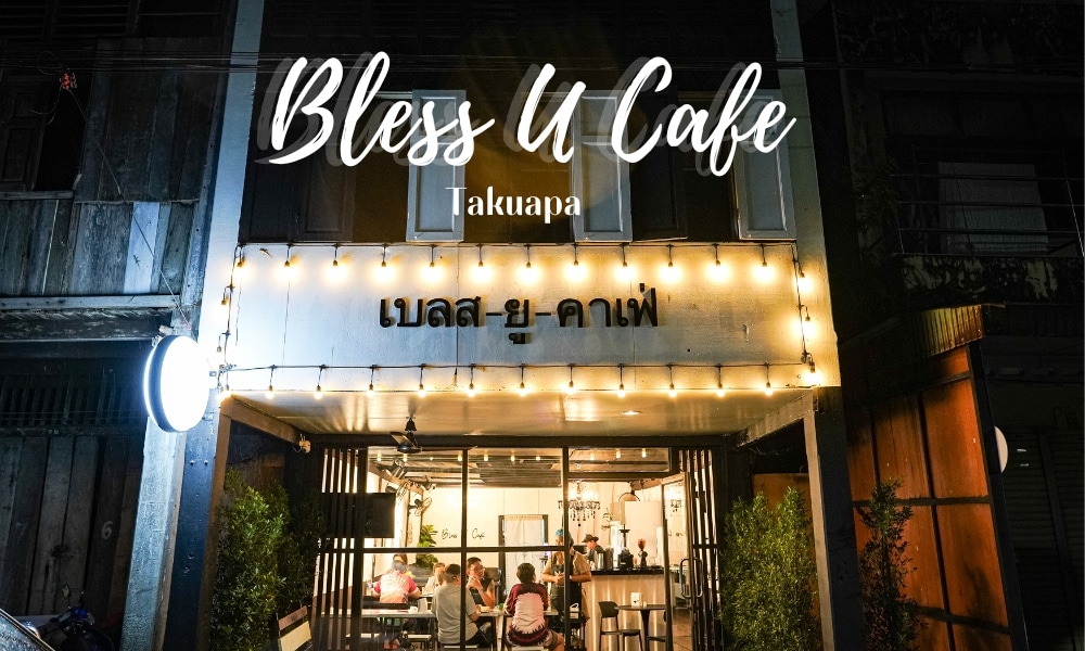 บริเวณด้านนอกของร้าน "Bless U Cafe" คาเฟ่ตะกั่วป่า ในตะกั่วป่า โดดเด่นด้วยดีไซน์ทันสมัยพร้อมไฟประดับที่ส่องประกายแวววาว ภายในคุณสามารถเห็นผู้คนเพลิดเพลินกับบรรยากาศที่มีชีวิตชีวา