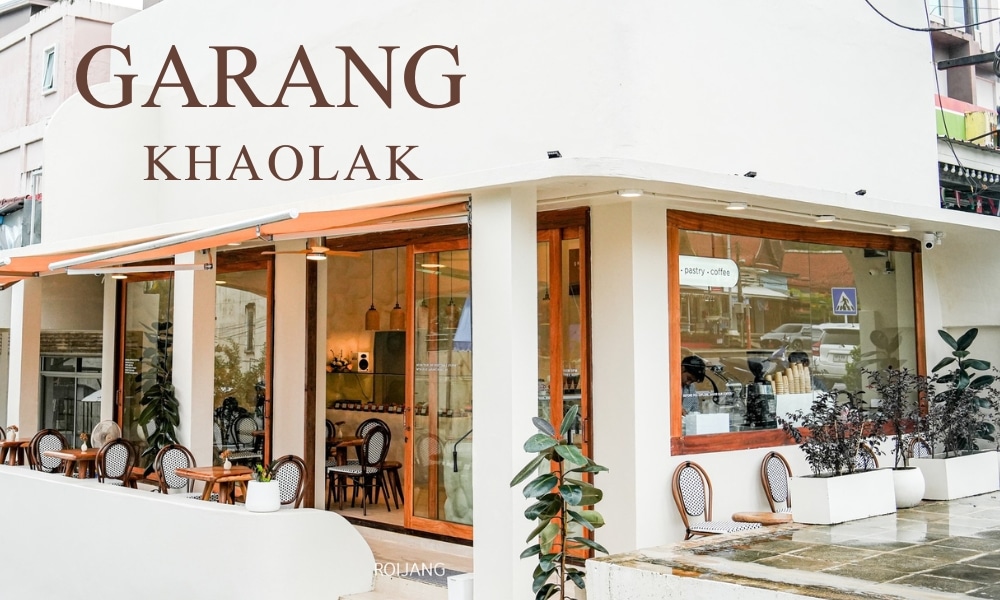  คาเฟ่เขาหลัก ภายนอกของคาเฟ่ Garang Khaolak นั้นมีหน้าต่างบานใหญ่ ที่นั่งกลางแจ้งที่น่าดึงดูด พร้อมด้วยเก้าอี้และโต๊ะสุดเก๋ และการประดับตกแต่งต้นไม้เขียวชอุ่มที่สร้างบรรยากาศที่เงียบสงบ