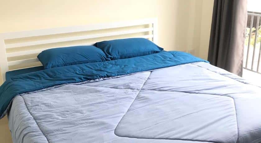 เตียง ที่พักใกล้อิมแพคเมืองทองธานี พร้อมผ้าห่มนวมสีน้ำเงินและหมอนสองใบ