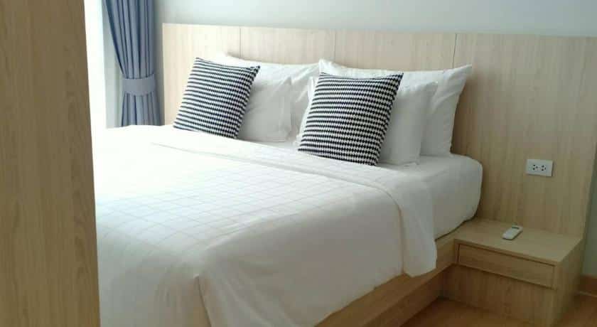 เตียง โรงแรมศรีราชาติดทะเล พร้อมผ้าปูที่นอนสีขาวและหมอนสีดำและสีขาว