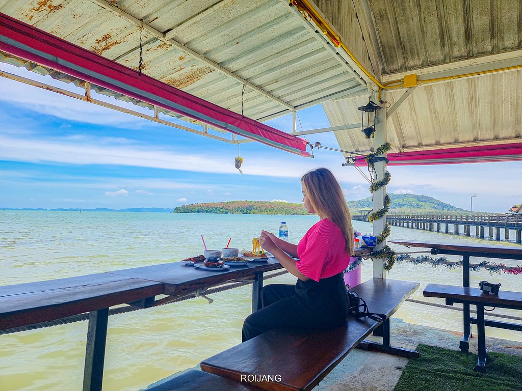 ผู้หญิงกำลังนั่งอยู่ที่โต๊ะทาน ของกินภูเก็ต ริมชายหาด