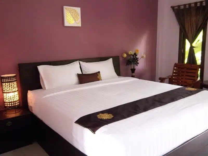 ห้อง โรงแรมในชัยภูมิ นอนพร้อมเตียงและโต๊ะพร้อมโคมไฟ