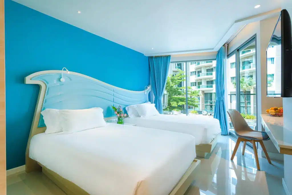 ห้องพักในโรงแรม ที่พักศรีราชาติดทะเล ที่มีสองเตียงและทีวีจอแบน