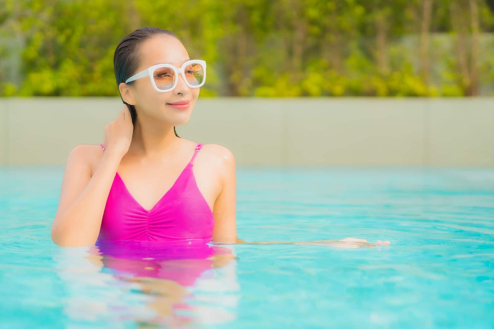 ผู้หญิงในชุดว่ายน้ำสีชมพูในสระ