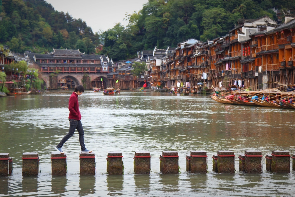 ชายคนหนึ่งกำลัง สถานที่ท่องเที่ยวจีน เดินข้ามสะพานข้ามแม่น้ำ