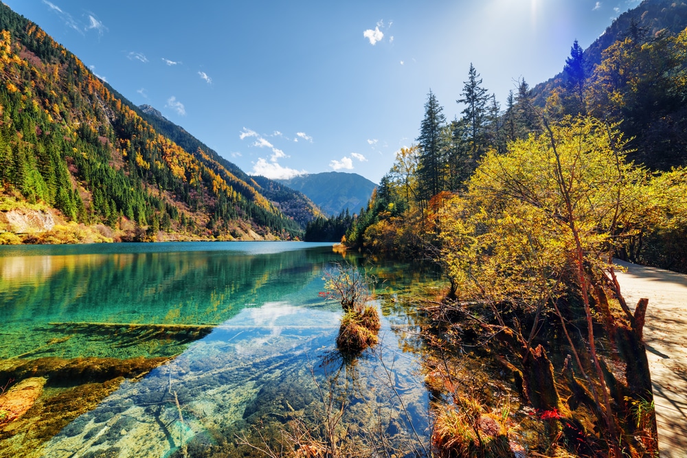 ทะเลสาบที่ล้อมร สถานที่ท่องเที่ยวจีน อบด้วยภูเขาและต้นไม้ในวันที่แดดจ้า