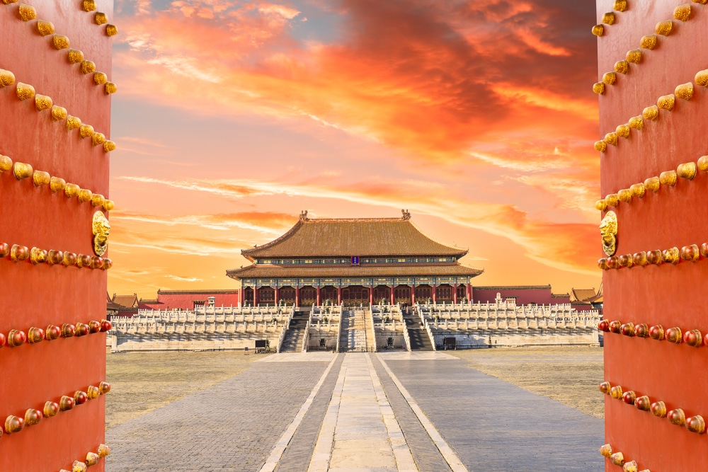 ประตูเปิดที่นำ สถานที่ท่องเที่ยวจีน ไปสู่อาคารที่มีพระอาทิตย์ตกดินเป็นฉากหลัง