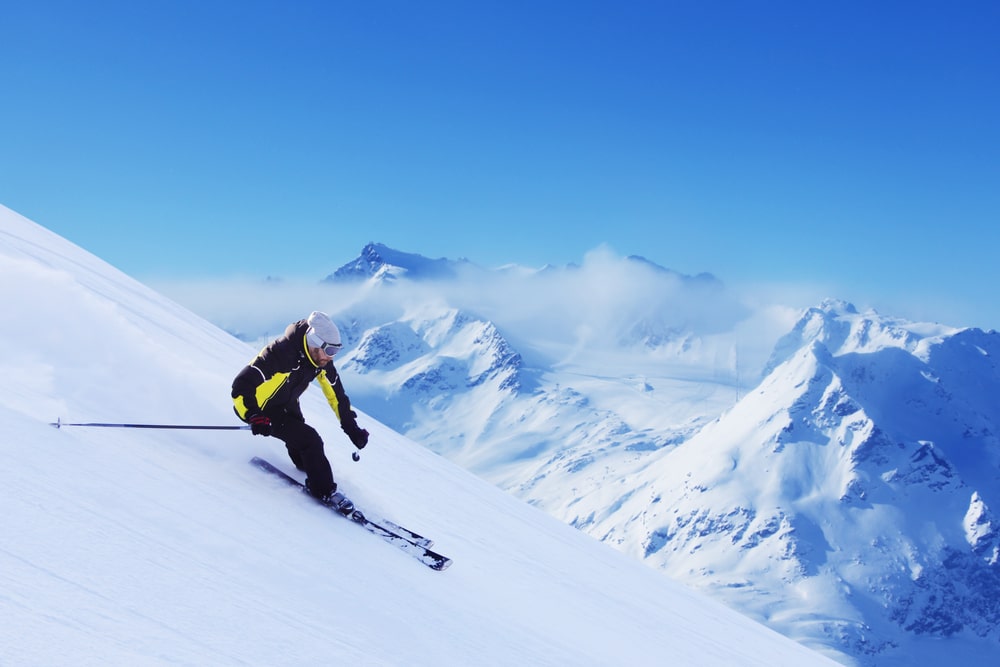 ชายคนหนึ่งกำลังเล่นสกีลงข้างทางลาดที่ปกคลุมไปด้วยหิมะ ที่เที่ยวออสเตรีย