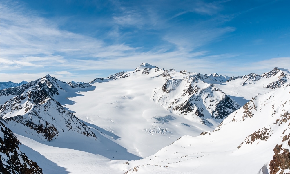 ชายคนหนึ่ง ที่เที่ยวออสเตรีย กำลังเล่นสกีบนเนินที่ปกคลุมด้วยหิมะ
