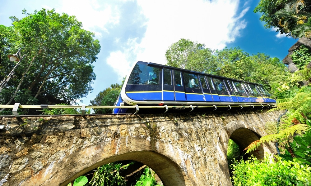 รถไฟสีน้ำเงิน ที่เที่ยวมาเลเซีย และสีขาวกำลังแล่นอยู่บนสะพาน