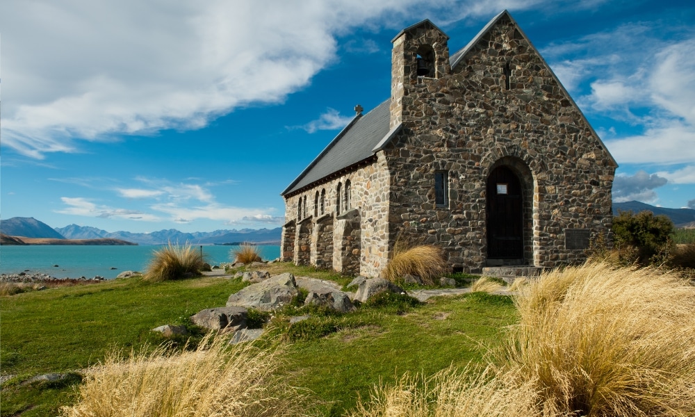โบสถ์ สถานที่ท่องเที่ยวนิวซีแลนด์ หินบนเนินหญ้าข้างแหล่งน้ำ