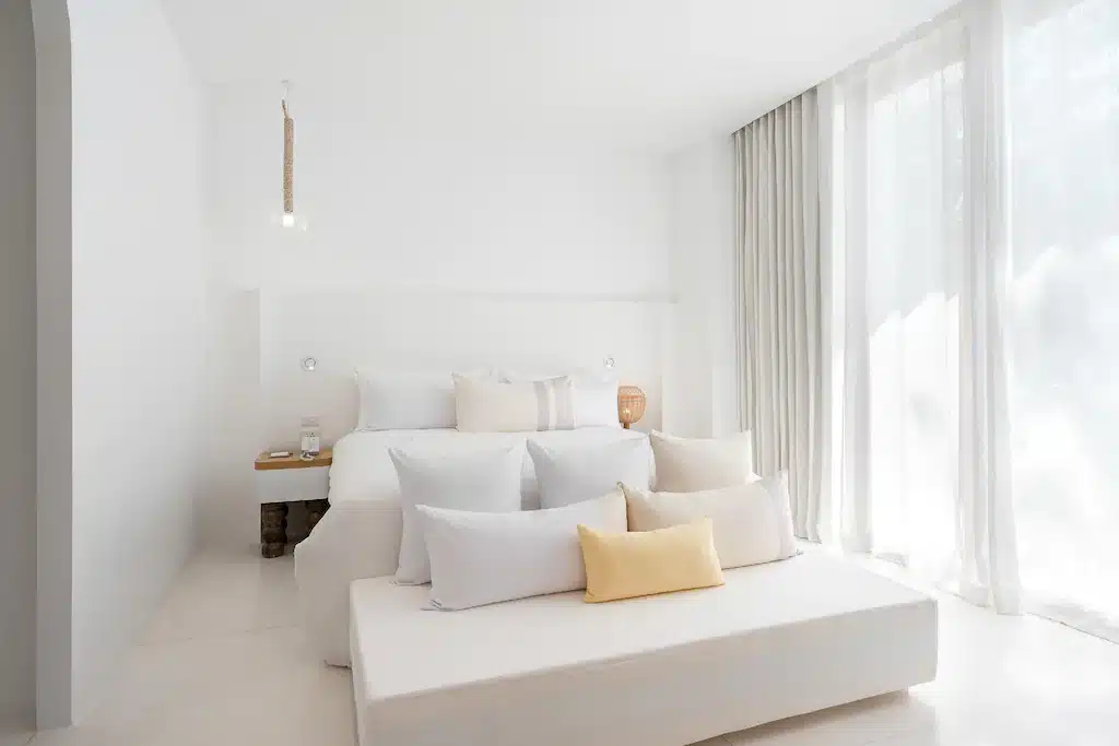 เตียงสีขาวนั่งอยู่ในห้องนอนข้างหน้าต่าง ที่พักสมุย
