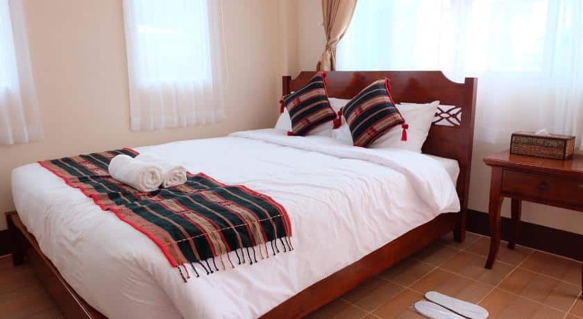 เตียงที่มี วัดร่องขุ่น หมอนสองใบและผ้าห่มอยู่ด้านบน