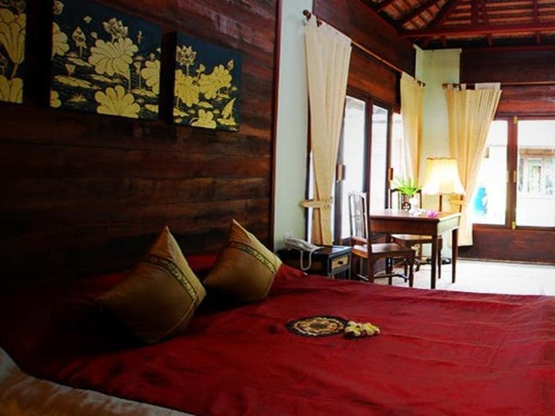 ห้องนอนที่มีเตียงสีแดงและผนังไม้ รีสอร์ทกำแพงแสน