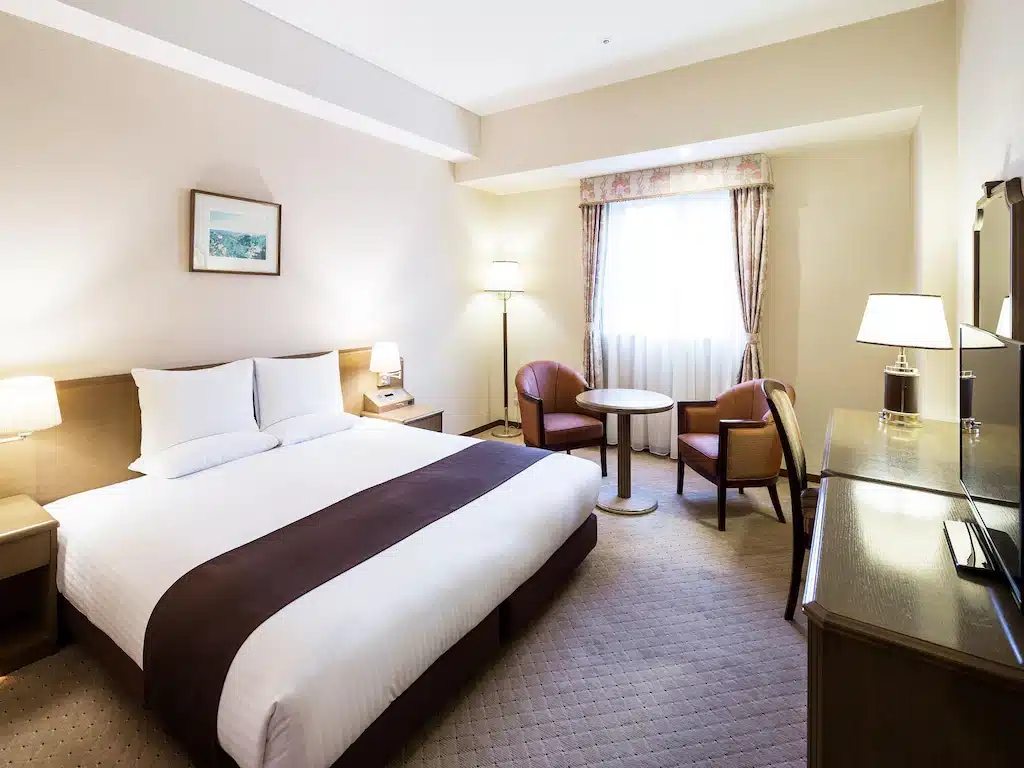 ห้องพักใน ที่เที่ยวฮอกไกโด โรงแรมที่มีเตียง โต๊ะ เก้าอี้และโทรทัศน์