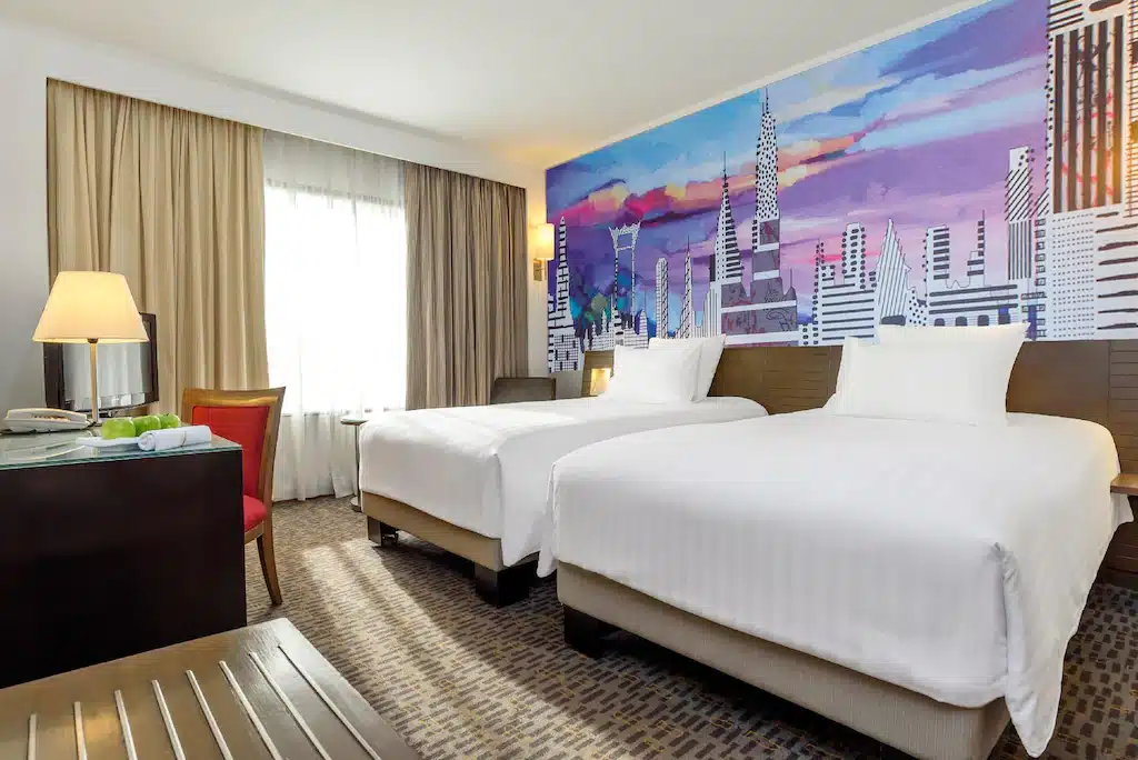 ห้องพักในโรงแรมที่มีสองเตียงและภาพวาดบนผนัง โรงแรมแถวสยาม